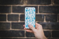 Hand holding Apple iPhone 6 plus with blue pattern on case.