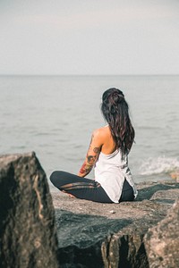 Free tattooed woman doing yoga on the cliffs by the sea public domain CC0 photo.