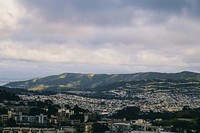 View of the hills of San Francisco against a cloudy blue sky.