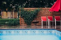 The clean pavement beside a crisp blue outdoor pool looks slick during a rainy afternoon, free public domain CC0 image.