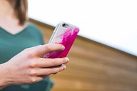 A close-up with a low focal range, of a woman texting on an iPhone 6 in a pink and white phone case.