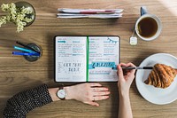 Free woman writing in notebook at work desk during breakfast photo, public domain CC0 image.