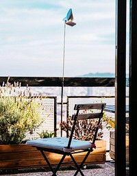 A sunny balcony features a patio chair and plants, free public domain CC0 image.