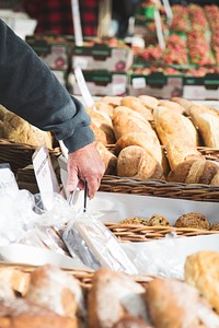 Free baker using tongs to pick up baked goods at a market image, public domain food CC0 photo.