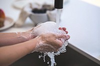 Soap bubbles gather in a pair of hands as they are washing in the kitchen.