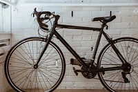 Free black bicycle against a white wall image, public domain vehicle CC0 photo.