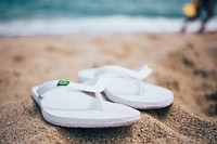 Free pair of white summer shoes rest in the sand, public domain CC0 photo image.