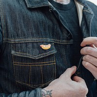 Fashionable man, wearing an enamel hotdog pin, unbuttoning his denim shirt.