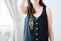Woman holding dream catcher pendant necklace in front of her