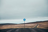 A lone sign managing the lone dark dirt road through the hillside of Iceland, free public domain CC0 image.