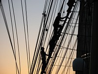 Crew member climbing up during sunset. Original public domain image from Flickr