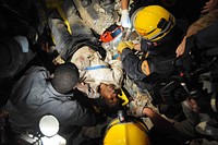 Members of the Los Angeles County Fire Department Search and Rescue Team rescue a Haitian woman from a collapsed building in downtown Port-au-Prince, Haiti, Jan. 17, 2010.