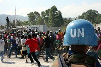 A Sri Lanka soldier attached to the United Nations forces in Haiti watches as a mob-like crowd surges to the check point where Haitians presented a food voucher to receive rations at a distribution point in Carrefour, Haiti.