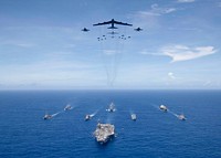 The aircraft carrier USS Ronald Reagan (CVN 76), foreground, leads a formation of Carrier Strike Group Five ships as Air Force B-52 Stratofortress aircraft and Navy F/A-18 Hornet aircraft pass overhead for a photo exercise during Valiant Shield 2018 in the Philippine Sea Sept. 17, 2018.