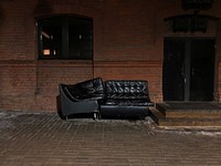 Black couch in front of brick wall. Free public domain CC0 image.