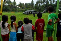 Local Children Watch a Member from Helicopter Sea Combat Squadron 23 “Wild Cards” Carry Float Coats for Passengers