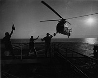 Landing signal officer (center) aboard the Navy Hospital Ship Repose off Vietnam directs a U.S. Marine Helo bringing battle casualties to the &quot;Angel of the Orient.&quot; [Helicopters.][Hospital ships. Transport of sick and wounded.][Scene.] Repose (AH-16) VietnamVNT-16324-F-10-67; By JOC Robert D. Moeser, U.S. Navy Medicine Historical Files Collection - Hospital Ship series.