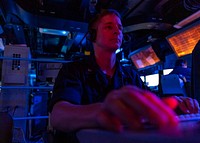 BAB AL-MANDEB STRAIT (Dec. 17, 2019) Cryptologic Technician (Technical) 3rd Class Christopher Braatenkapsch stands the electronic warfare console operator watch in the combat information center of the guided-missile cruiser USS Normandy (CG 60) as the ship transits the Bab al-Mandeb Strait.