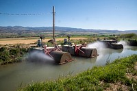 P&J Ranches Producer Steve Burke (black baseball cap) and other landowners use water from the Ruby Reservoir at the base of the Ruby Mountains where water flows along the West Bench Canal, just above the mountain base, above the farmlands; along the way, improved U.S. Department of Agriculture (USDA) funded control valves allow water through debris grates and additional (self-cleaning) rotating cylindrical algae filter screens before entering inlets to funded Irrigation Water Management systems and into the (gravity-flow) Irrigation Pipeline that supplies five center-pivot and one wheel-line Sprinkler System without the use of pumps in Sheridan, MT, on August 28, 2019.