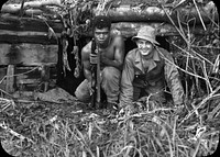 Medical personnel pose with a Papua New Guinea military member kneeling in the entrance of a dugout. [Personnel][Foreign National][Ordnance][Papua New Guinea][World War II] World War II - Bougainville - November to December 1943 Alt Collection. Original public domain image from Flickr