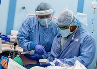 200409-N-PH222-1106 LOS ANGELES (April 9, 2020) Cmdr. Youwei Lin, from Lexington, Mass. (left) and Lt. Cmdr. Trevares Baker, from Pensacola, Fla., monitor patient information during a surgery aboard the hospital ship USNS Mercy (T-AH 19).