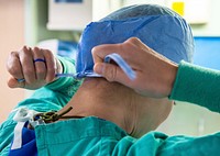 USNS Mercy Perioperative Nurse 200417-N-DA693-1008 LOS ANGELES (April 17, 2020) Lt. Cmdr. Amanda Kuczka, from Kansas City, Mo., a perioperative nurse assigned to hospital ship USNS Mercy (T-AH 19), ties her hair cover prior to entering an operating room on April 17.