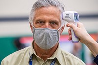 Man wearing a mask during the COVID-19 pandemic has his temperature checked. Original public domain image from Flickr