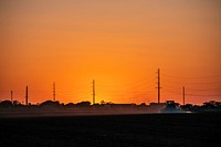 Sunset on a sprayer in the field, near power lines and towers, Hondo, Texas, on April 9, 2021. USDA Photo/Media by Lance Cheung. Original public domain image from Flickr