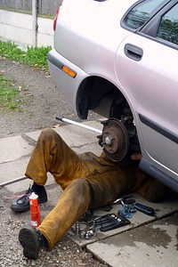 Man repairing car lying on ground. Original public domain image from Flickr
