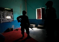 Ugandan soldiers serving with the African Union Mission in Somalia (AMISOM) 33rd Battalion stand inside an abandoned house . Original public domain image from Flickr