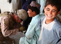 Cheesin'A young boy smiles for the camera while Petty Officer 3rd Class Brandon Dixon, a Navy corpsman with Guard Force, 1st Battalion, 6th Marine Regiment, treats a teenager’s foot injury during a patrol here, July 29.