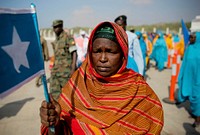 A woman holds the Somali flag at Mogadishu International Airport during a ceremony held 25 March to recieve the casket containing the body of fomer Somali president Abdullahi Yusuf Ahmed who died aged 77 at a hospital in the Gulf State of Abu Dhabi 23 March.