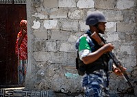A young Somali woman looks on as a Ugandan police officer serving as part of a Formed Police Unit (FPU) with the African Union Mission in Somalia (AMISOM) walks past during a foot patrol in the Kaa&#39;ran district in the Somali capital Mogadishu 09 November 2012. Original public domain image from <a href="https://www.flickr.com/photos/au_unistphotostream/8171794924/" target="_blank">Flickr</a>
