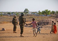 A young Somali boy greets a Ugandan soldier serving with The African Union Mission in Somalia (AMISOM) in the central Somali town of Buur-Hakba following it&#39;s capture the day before from the Al-Qaeda-affiliated extremist group Al Shabaab by the Somali National Army (SNA), supported by AMISOM forces. Original public domain image from <a href="https://www.flickr.com/photos/au_unistphotostream/8550239341/" target="_blank">Flickr</a>