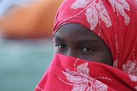 A Somali IDP stands outside of her home in the garden of Mogadishu's now-destroyed cathedral, built by the Italians during colonialism, in Hamar weyn district on May 22. AU UN IST PHOTO / Ilyas A. Abukar. Original public domain image from Flickr