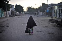 A woman walks down the street just after sunrise in Somalia's capital, Mogadishu. Original public domain image from Flickr