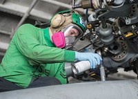 U.S. Navy Aviation Electrician's Mate 2nd Class Mark Monbleau spray-paints an HH-60H Sea Hawk helicopter assigned to Helicopter Anti-submarine Squadron (HS) 5 in the hangar bay of the aircraft carrier USS Dwight D. Eisenhower (CVN 69) in the Atlantic Ocean June 24, 2013.
