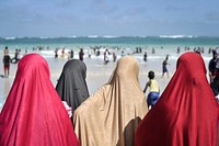 Women dressed for Eid watch as hundreds of Somalis play in the surf at Lido beach in Mogadishu, Somalia. Original public domain image from Flickr