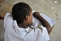 A young boy writes in his excercise book during class at as school run by the Abdi Hawa Center in the Afgoye corridor of Somalia, on September 25. Original public domain image from Flickr