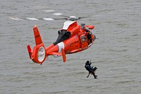 A Coast Guard K-9 handler with the Marine Safety and Security Team in Galveston, Texas and his dog are lowered to boat from a Coast Guard MH-65 Dolphin from Air Station Houston, Feb. 7, 2014.