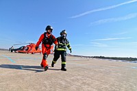 Raymond Cifelli, a civilian fire protection specialist from the New Jersey Air National Guard's 177th Fighter Wing, assists a U.S. Coast Guard aviator during an air mishap exercise at Coast Guard Air Station Atlantic City on Feb. 11, 2014.