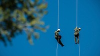 Veteran wildland firefighter rappellers use various techniques to negotiate the wind from the helicopter rotor blades above them, and away from tree branches, beside and below, as they perform a controlled and safe rappel at the U.S. Department of Agriculture (USDA) U.S. Forest Service (USFS) National Helicopter Rappel Program&rsquo;s Rappel Academy at Salmon Air Base in Salmon, ID on Thursday, May 15, 2014.