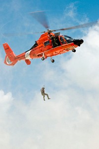 A U.S. Coast Guard rescue swimmer is lowered to a beach from an MH-65 Dolphin helicopter at San Luis Pass in Texas, May 24, 2014.