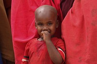 A young boy looks on as residents in Baidoa prepare to welcome Prime Minister Abdiweli Sheikh Ahmed during his trip to Baidoa. AMISOM Photo / Ilyas A. Abukar. Original public domain image from Flickr