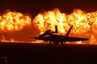 Playing With Fire. Flames explode behind the U.S. Navy Blue Angels' F/A-18 Hornets during the night portion of the 2014 Miramar Air Show aboard Marine Corps Air Station Miramar, Calif. The wall of fire is the last event of the night air show. Original public domain image from Flickr