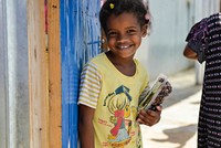 A young girl smiles after receiving a packet of dates from AMISOM's Woman & Child Protection Office, Kaoutar Kaddouri, during a distribution of dates to less fortunate families around Mogadishu by the AMISOM Gender Unit on 3rd July 2014.