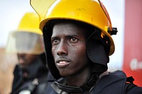 A Somali civil aviation firefighter listens to instructions during a fire fighting drill in Mogadishu, Somalia on July 14 2015. The training was supported and organised by the United Nations Support Office for AMISOM (UNSOA) and facilitated by African Union Mission in Somalia (AMISOM). UN photo / Ilyas Ahmed. Original public domain image from Flickr