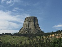 Devils Tower is an eroded laccolith in the Black Hills of Wyoming. A laccolith forms when molten magma forces its way into a rock formation, then cools and hardens. As the surrounding rock erodes away over time, the hardened former magma remains. The streaked surface of Devils Tower reflects the polygonal shaped fractures (columnar joints) that formed as magma contracted as it cooled and hardened. Devils Tower rises 1,267 feet above the nearby Belle Fourche River and according to the National Park Service, the summit is roughly the size of a football field. Photo credit: Alex Demas, USGS. Original public domain image from Flickr