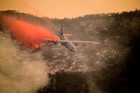A U.S. Air National Guard C-130J Hercules aircraft equipped with the MAFFS 2 (Modular Airborne Fire Fighting System) drops a line of fire retardant on the Thomas Fire in the hills above the city of Santa Barbara, California, Dec. 13, 2017.