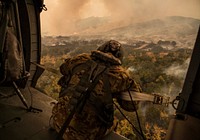 U.S. Army Sgt. Anthony Orduno, a UH-60 Black Hawk helicopter crew chief with Bravo Company, 1st Battalion, 140th Aviation Regiment, California Army National Guard looks out while flying over the Thomas Fire, Dec. 9, 2017, in Ventura County, California.